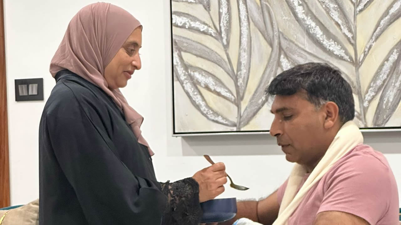 Son épouse l'aidant à manger. 