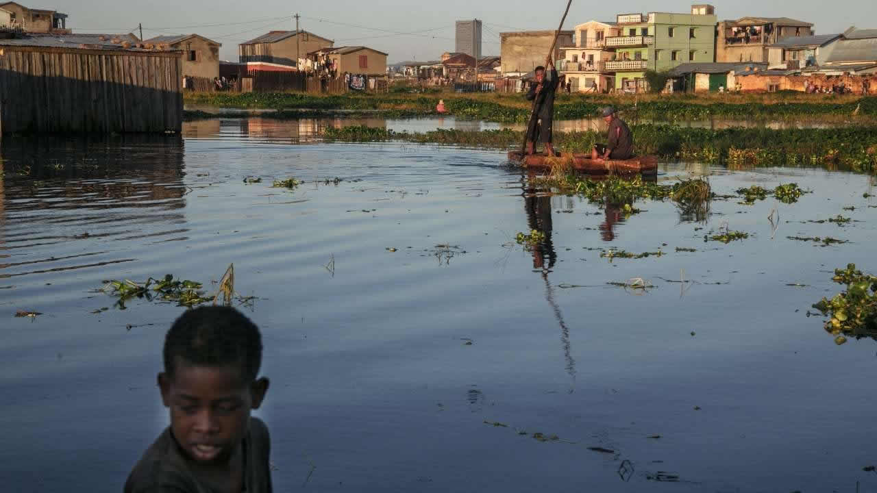 Des habitants du quartier inondé d'Ankasina, utilisant des embarcations de fortune pour rejoindre leurs maisons à Antananarivo, le 28 janvier 2022