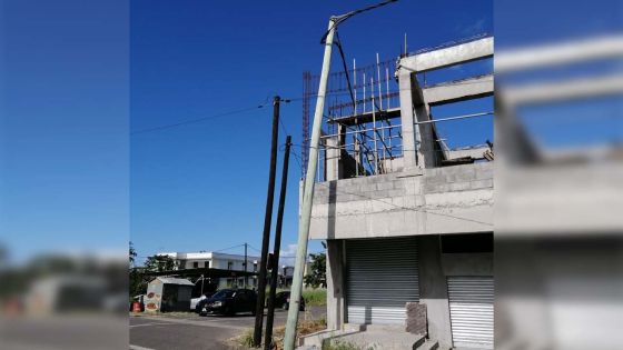 Un pylône électrique penche dangereusement sur une construction