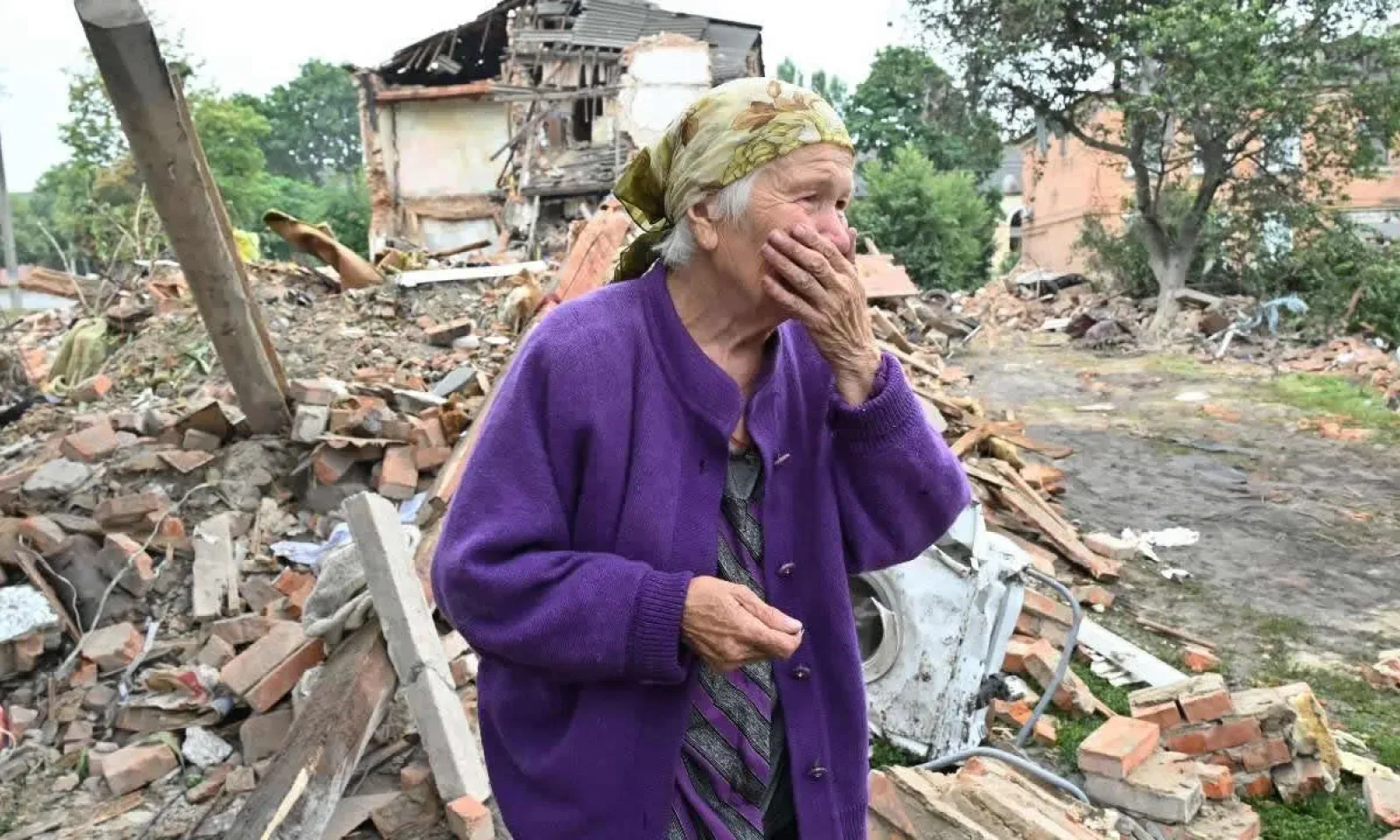 Raisa Kuval, 82 ans, réagit à côté d'un bâtiment endommagé partiellement détruit après un bombardement dans la ville de Chuguiv, à l'est de Kharkiv, en Ukraine, le 16 juillet 2022
