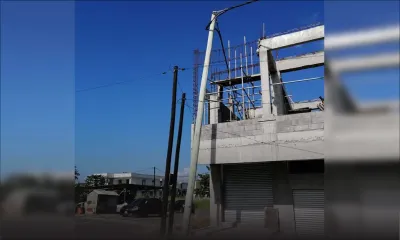 Un pylône électrique penche dangereusement sur une construction