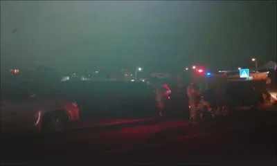 À Camp-Levieux, quatre membres de la SMF s'équipent pendant que leurs collègues lâchent des cartouches de gaz lacrymogène en arrière-plan.