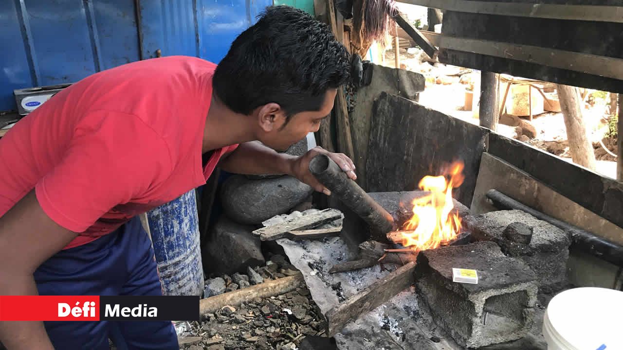 Kevin alimente le feu avec un « poukni ». Dans la mouise à La Ferme