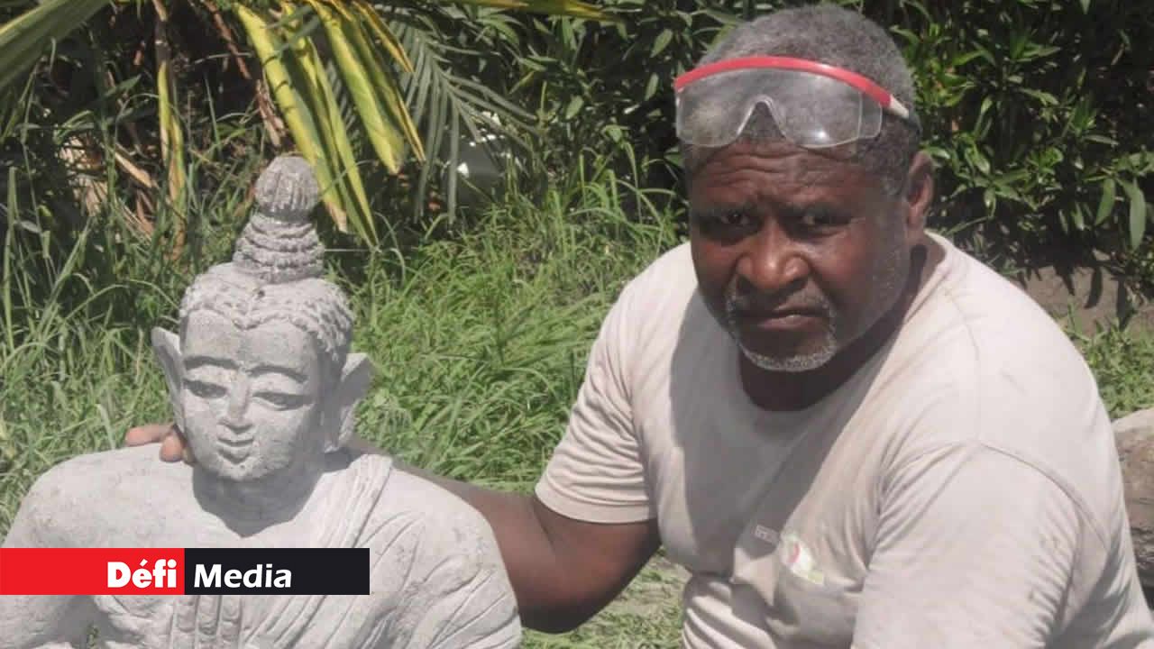 Jean Lewis Dick posant avec sa sculpture de Boudha en pierre. Jean Lewis Dick