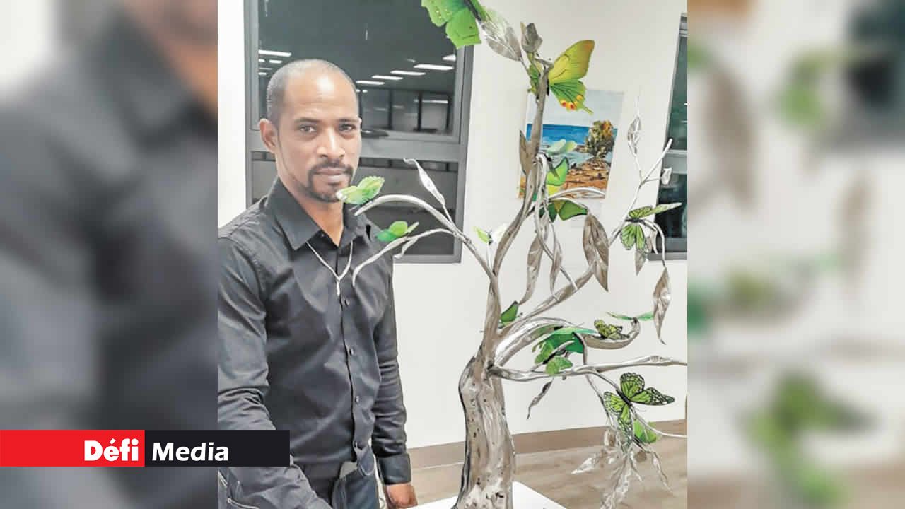 L’artiste et son œuvre « L’arbre de vie » ornée de papillons en inox coloré.