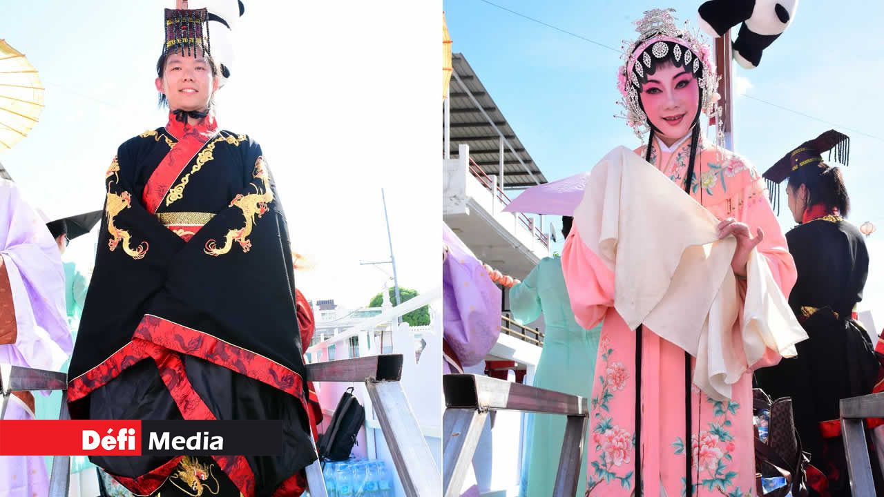 Cette personne est vêtue d’un costume traditionnel noir orné de dragons dorés, symbole de force et de sagesse. Une femme vêtue d’un habit rose fleuri, parée de sa coiffe chinoise et d’un maquillage impeccable, incarne la beauté intemporelle du Nouvel An chinois.