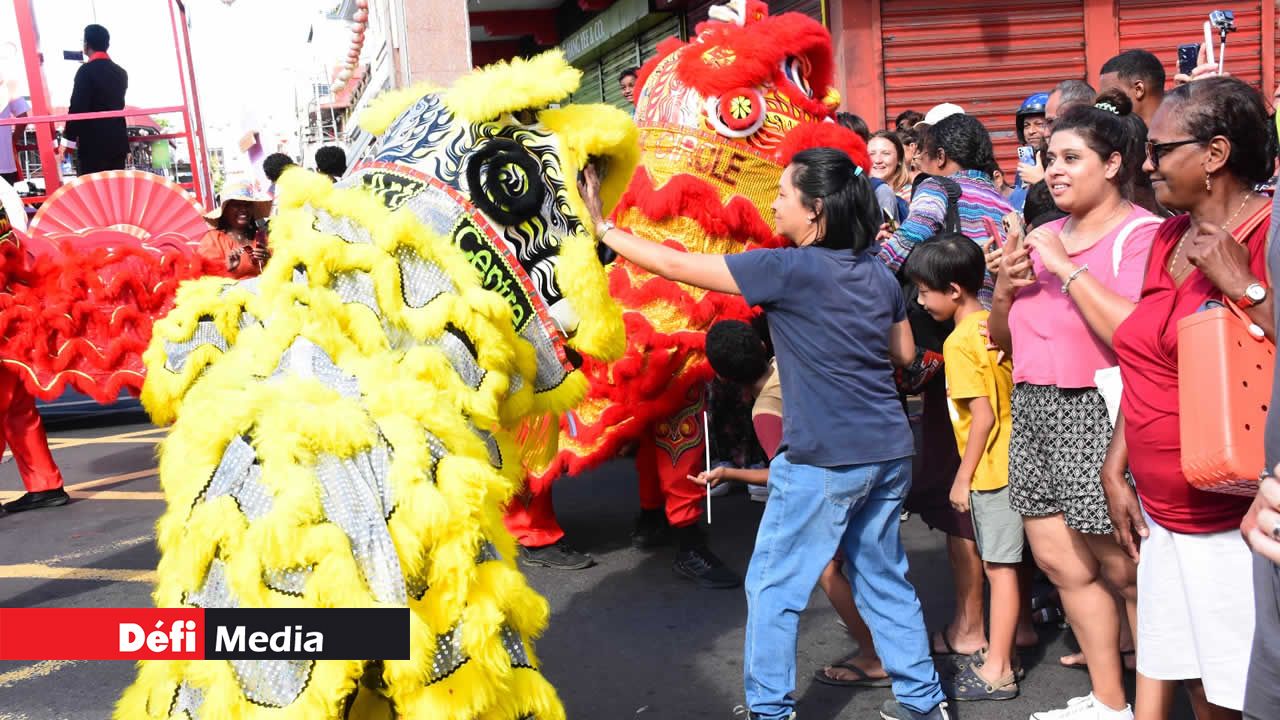 Un dragon chinois déployant sa majesté, tandis qu’une femme s’approche pour lui toucher la tête.